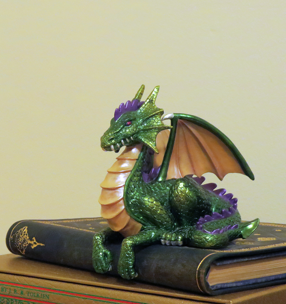 Green dragon shelf-sitter atop a pile of leatherbound books