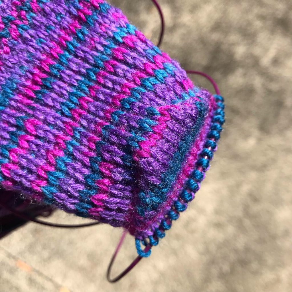 Heel of hand-knitted sock in progress, knit on circular needles in multicolor yarn.